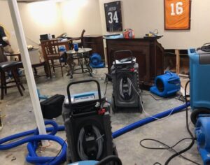 Water damage restoration process with industrial drying equipment and dehumidifiers in use